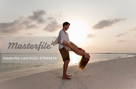 Couple playing on beach at sunset