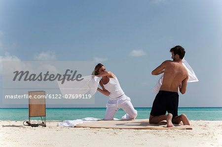 Couple having pillow fight on beach