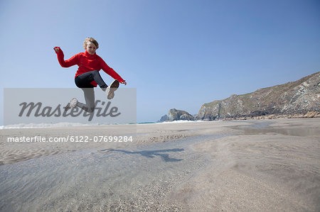 Boy jumping over pools on beach