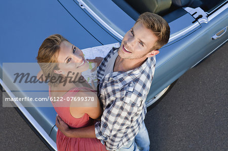 Couple hugging by convertible