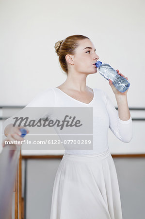 Ballet dancer drinking water in studio
