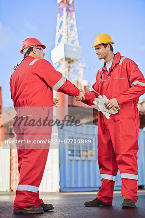 Workers shaking hands on oil rig