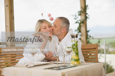 Couple in bathrobes kissing at breakfast