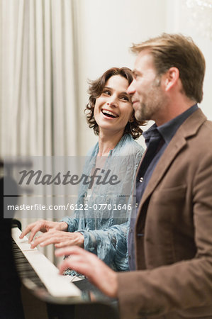 Couple playing piano together at home