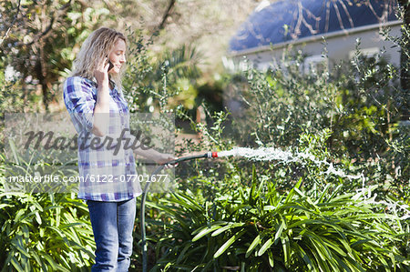 Woman on cell phone watering plants