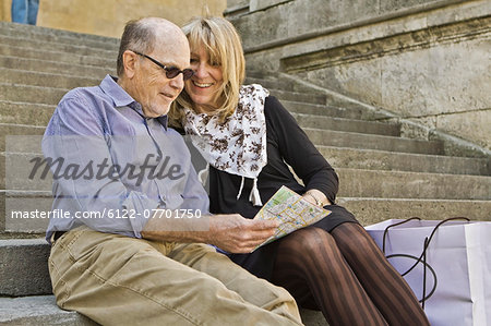 Older couple reading city map on steps