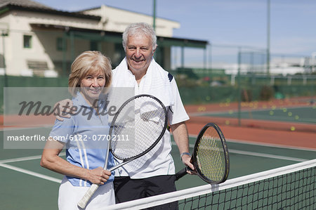 Older couple hugging on tennis court