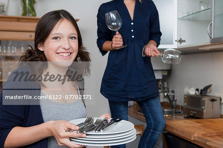 Smiling girls putting away dishes