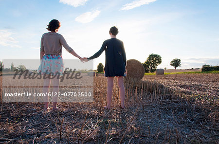 Girls holding hands in hay field
