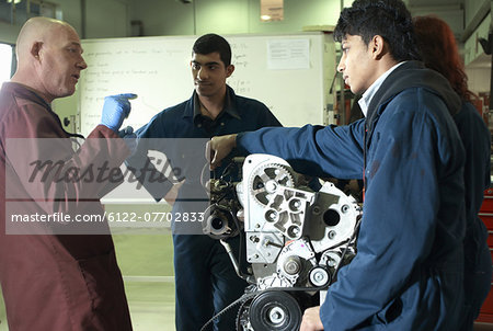 Teacher helping students with car engine