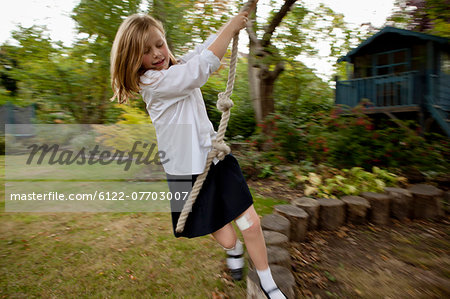 Girl playing on rope swing in backyard