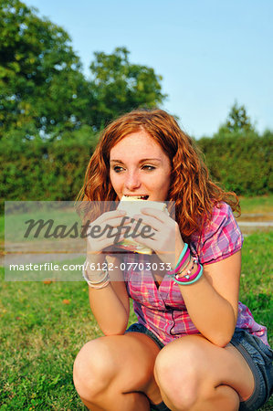 Teenage girl eating sandwich in backyard