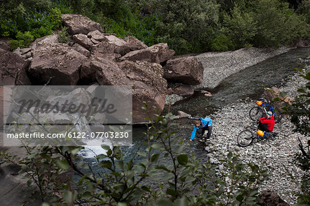 Couple crossing creek with bicycles