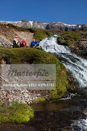 Hikers resting by waterfall