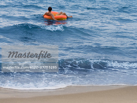 Man floating in inner tube in ocean