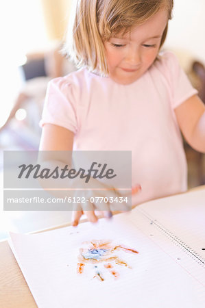 Girl finger-painting in notebook