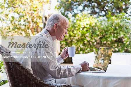 Older man using laptop outdoors