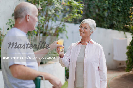 Older couple drinking juice in backyard