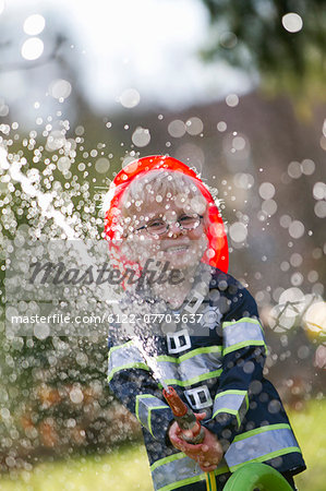 Boy in fireman costume playing with hose