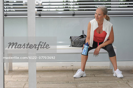 Older woman drinking water in gym