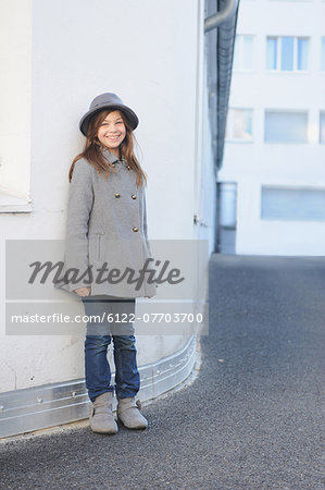 Smiling girl leaning on wall outdoors