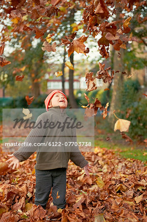 Boy playing in autumn leaves