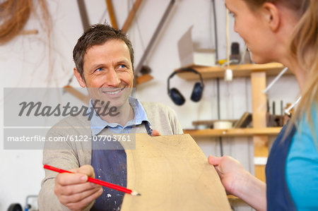 Carpenter giving blueprints to assistant