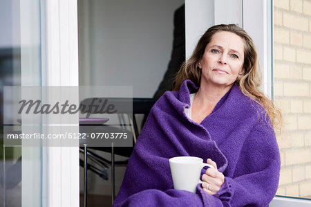 Woman with coffee in blanket outdoors