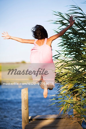 Woman jumping off dock into lake