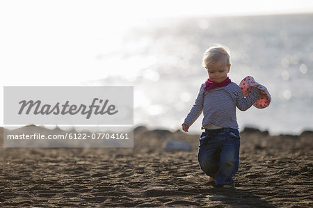 Toddler carrying sunhat on beach