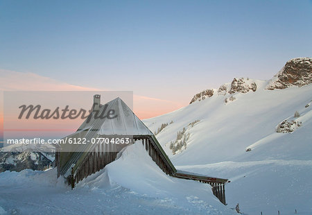 Snow piled up by house on hillside