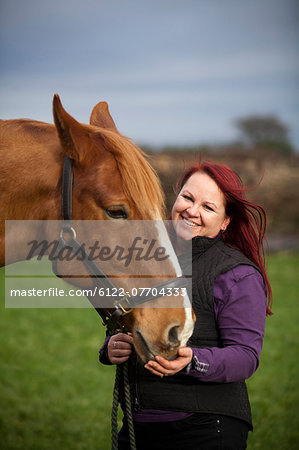 Woman walking horse in rural field