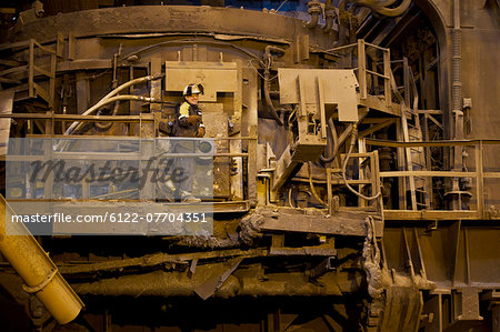 Worker using machinery in steel forge