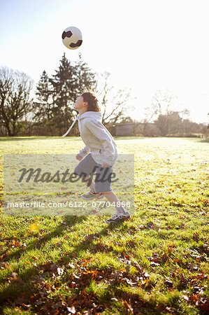 Boy playing with soccer ball in meadow