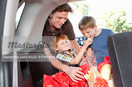 Boys eating groceries in trunk of car