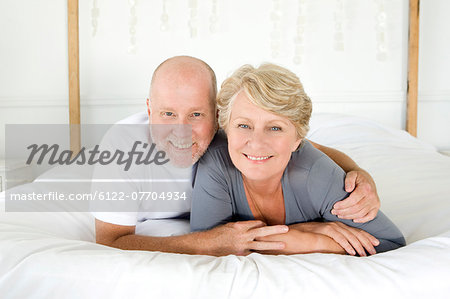 Smiling older couple laying on bed