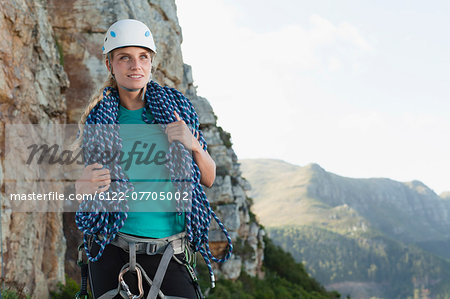 Climber holding coiled rope on mountain