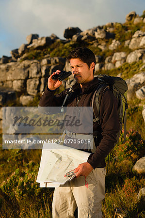 Hiker using binoculars in rocky field