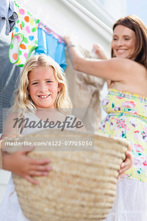 Girl helping mother hang laundry