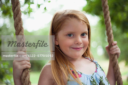 Smiling girl sitting in tree swing