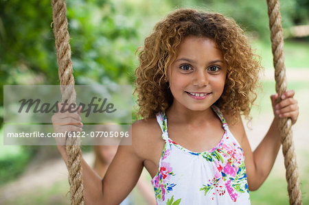 Smiling girl standing on tree swing