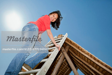 Woman climbing to roof of log hut