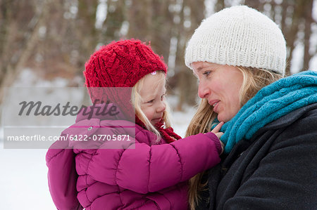 Mother carrying daughter in snow