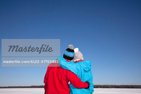 Couple hugging in snowy field