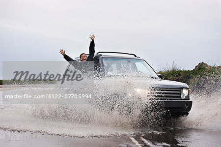 Man leaning out of splashing car