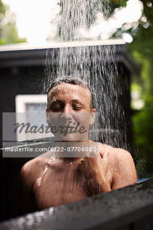 Teenage boy showering outdoors