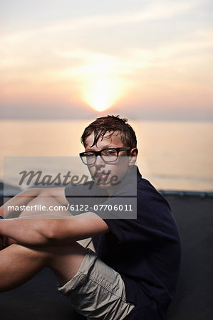 Teenage boy sitting on trampoline