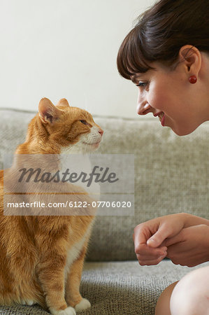 Woman talking with cat on sofa