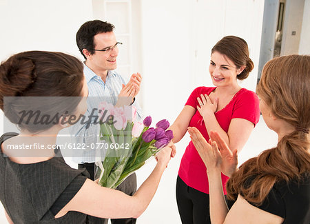 Business people giving colleague flowers