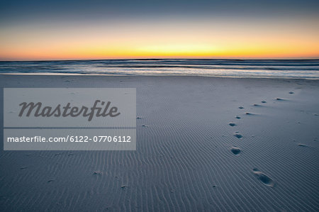 Footprints on sandy beach at sunrise